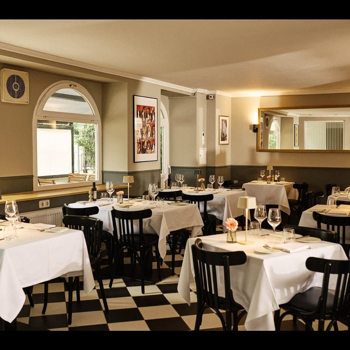 Comedor de Nanai con mesas puestas, suelo de damero y luz cálida