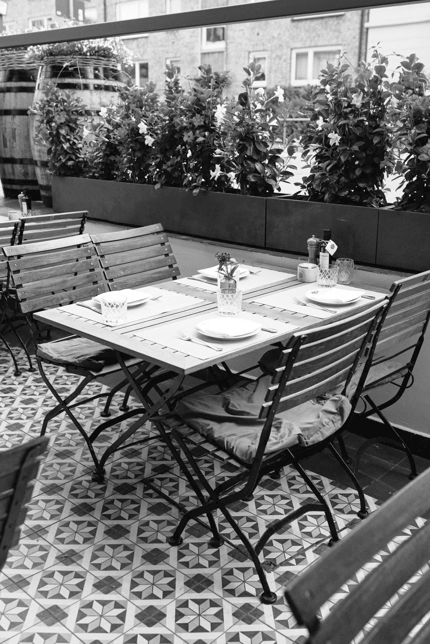 Terraza de Nanai en Winterhude con mesa puesta, sillas y jardineras